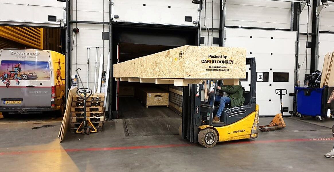 Heftruckhandling met exportkist in de loods van Cargo Donkey